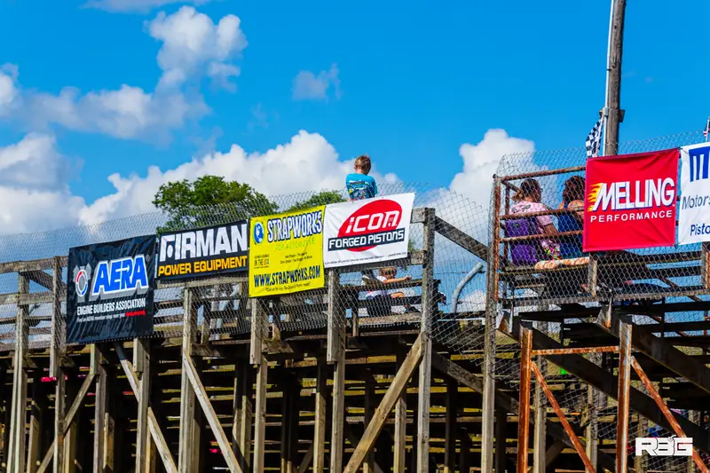 Sponsor banners hung along the grandstand rail with fans above